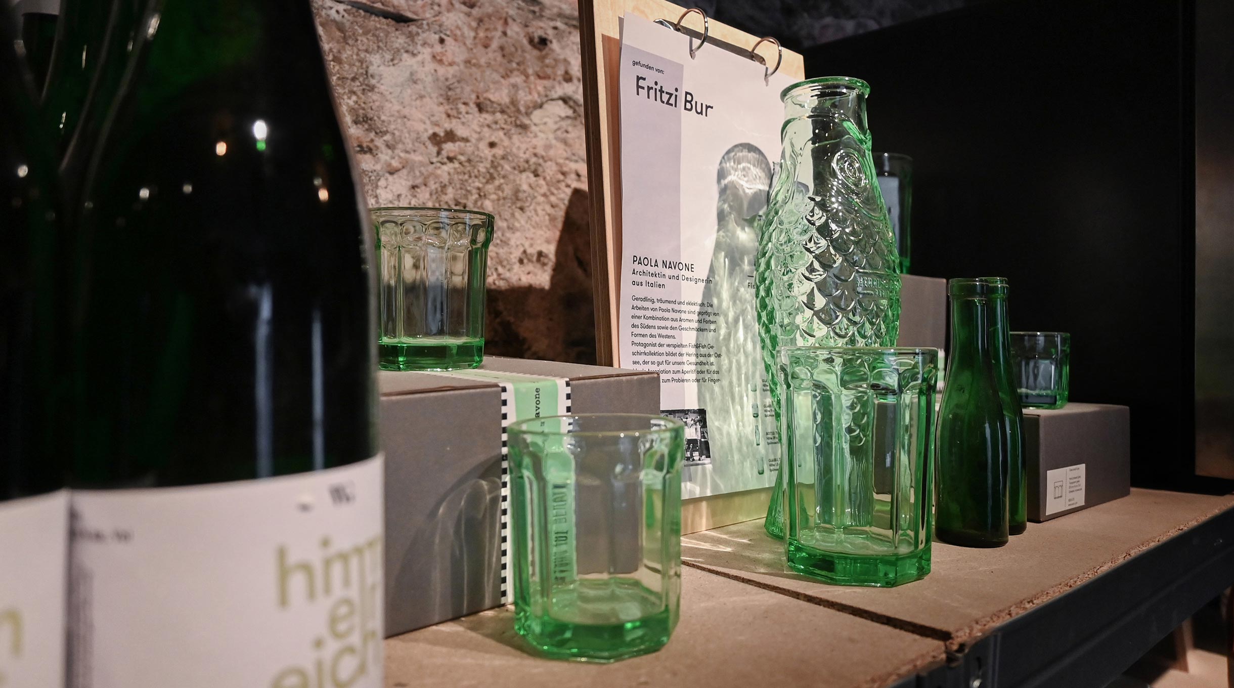 Dekorative Glasflaschen und Trinkgläser im Flaschenlager mit stilvoller Präsentation und historischem Natursteinmauerwerk.